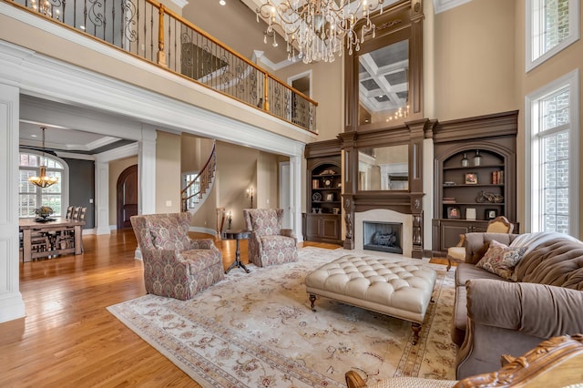 living room with ornamental molding, a healthy amount of sunlight, a fireplace with flush hearth, and an inviting chandelier