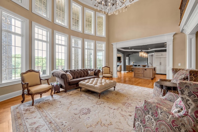 living room featuring light wood finished floors, a notable chandelier, and ornate columns