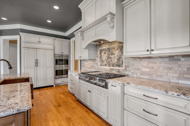 kitchen with appliances with stainless steel finishes, white cabinetry, and ornamental molding