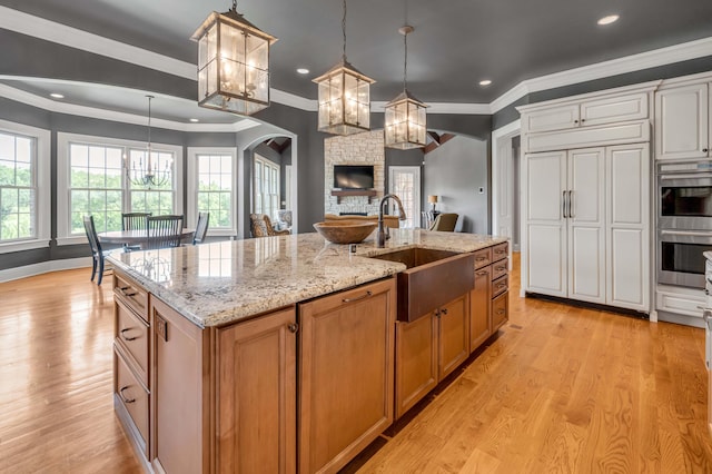 kitchen with decorative light fixtures, a large island, paneled built in fridge, brown cabinetry, and white cabinetry