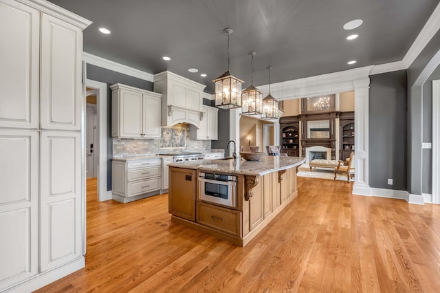 kitchen with white cabinetry, a center island with sink, stainless steel oven, and pendant lighting