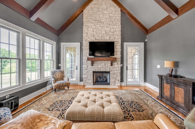 living area with high vaulted ceiling, a fireplace, wood finished floors, baseboards, and beamed ceiling