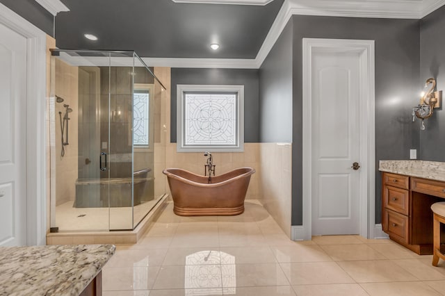 full bath featuring tile walls, ornamental molding, vanity, a shower stall, and a freestanding tub