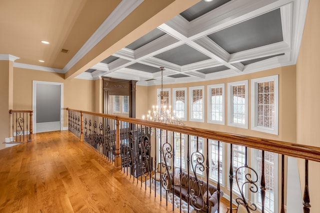 hallway with beam ceiling, coffered ceiling, light wood finished floors, and an inviting chandelier