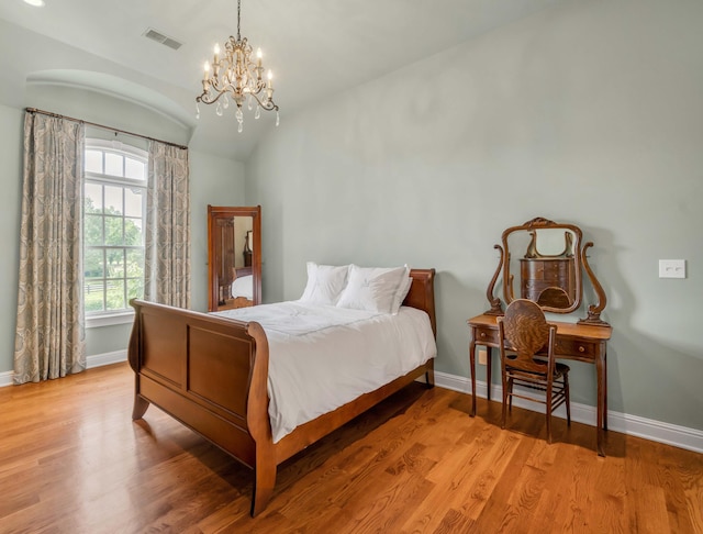 bedroom with light wood finished floors, baseboards, visible vents, and vaulted ceiling