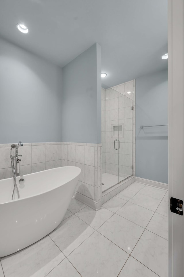 full bath with tile walls, a freestanding tub, and a shower stall