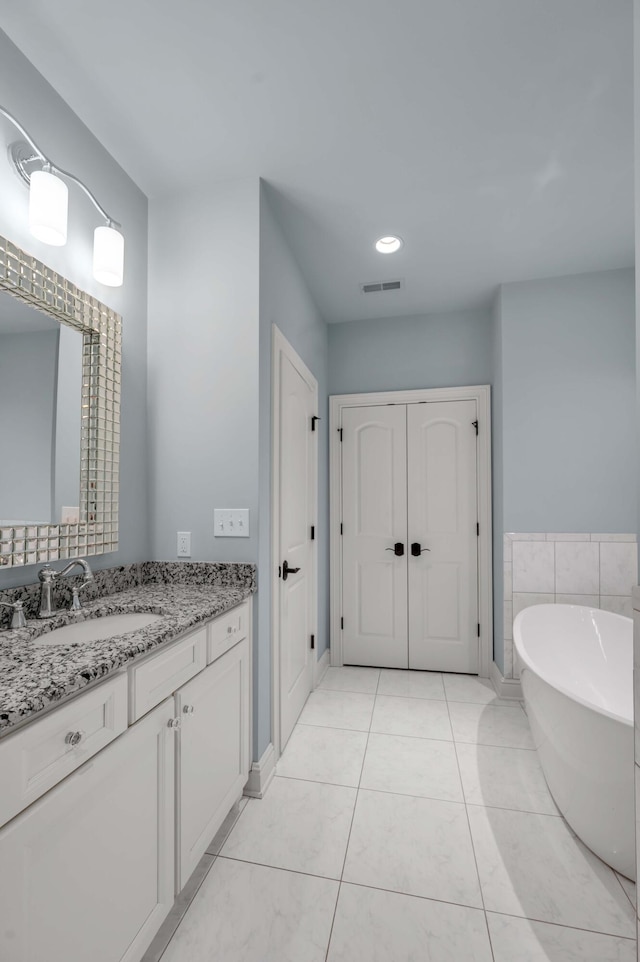 full bathroom featuring a closet, a soaking tub, visible vents, vanity, and tile patterned flooring