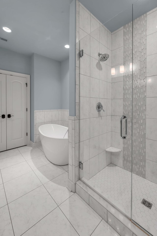 full bathroom with tile patterned flooring, visible vents, tile walls, a freestanding bath, and a shower stall