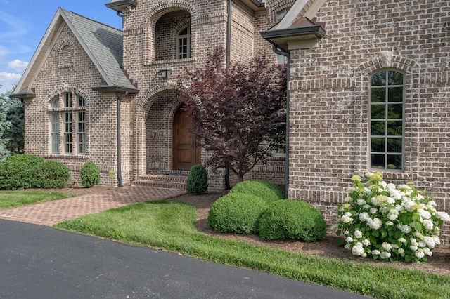 view of front facade featuring brick siding and roof with shingles