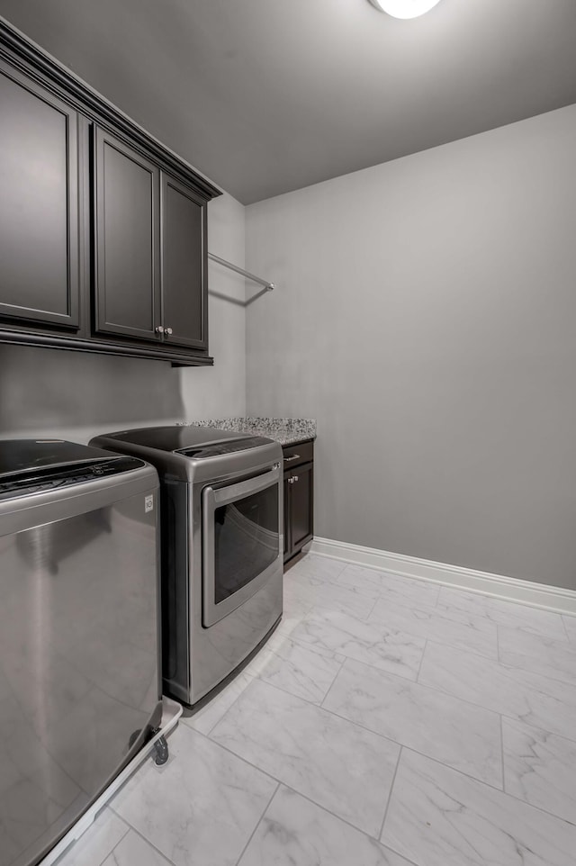 washroom with cabinet space, baseboards, marble finish floor, and washer and dryer