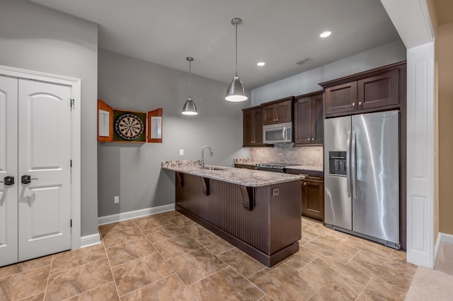 kitchen with a breakfast bar area, dark brown cabinetry, a peninsula, appliances with stainless steel finishes, and pendant lighting