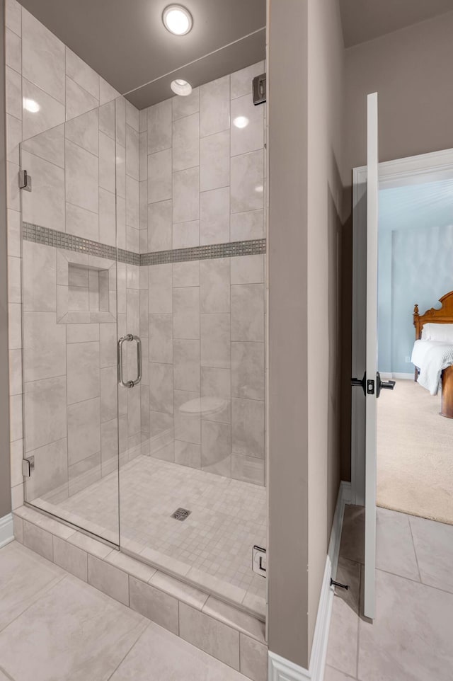 ensuite bathroom with a stall shower, baseboards, connected bathroom, and tile patterned floors