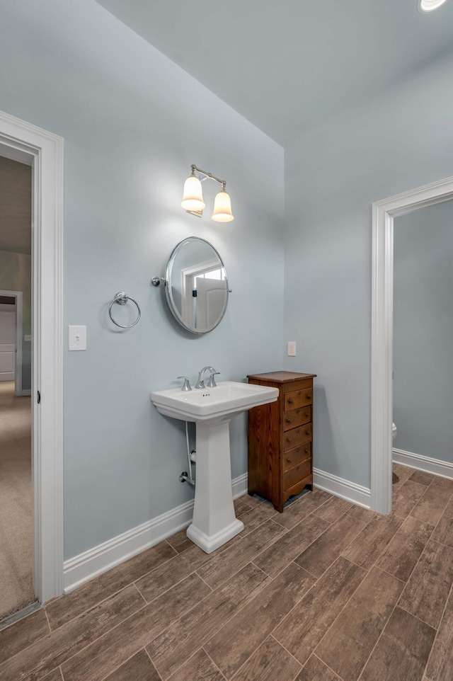 bathroom with toilet, baseboards, and wood finish floors