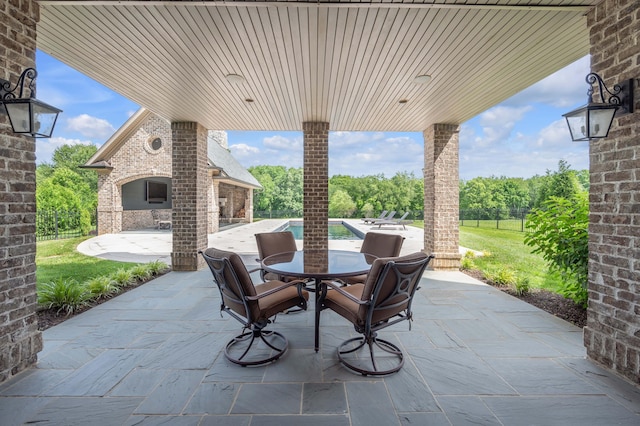 view of patio / terrace featuring an outdoor brick fireplace and fence