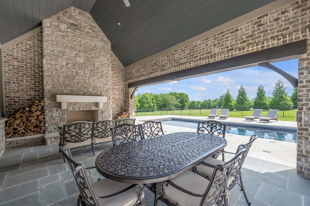 view of patio / terrace with an outdoor stone fireplace, fence, and a fenced in pool