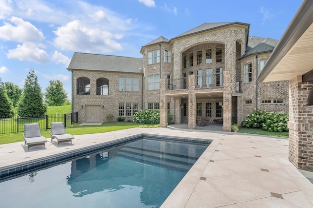 back of house featuring a patio, brick siding, fence, a lawn, and a fenced in pool