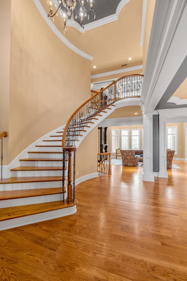 foyer entrance featuring an inviting chandelier, stairway, light wood finished floors, and arched walkways