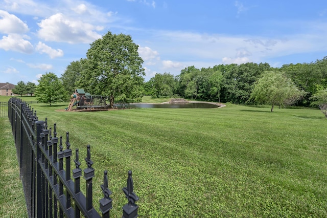 view of yard featuring a water view, fence, and playground community