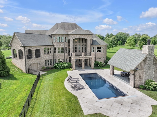 back of property with a balcony, fence, a lawn, an outdoor pool, and a patio area