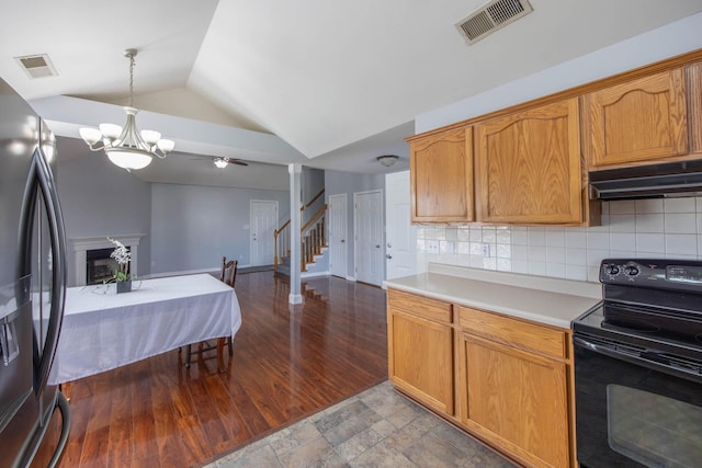 kitchen with black range with electric cooktop, under cabinet range hood, visible vents, light countertops, and stainless steel fridge