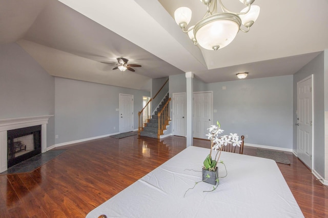 dining space featuring a fireplace with flush hearth, dark wood-type flooring, baseboards, and stairs