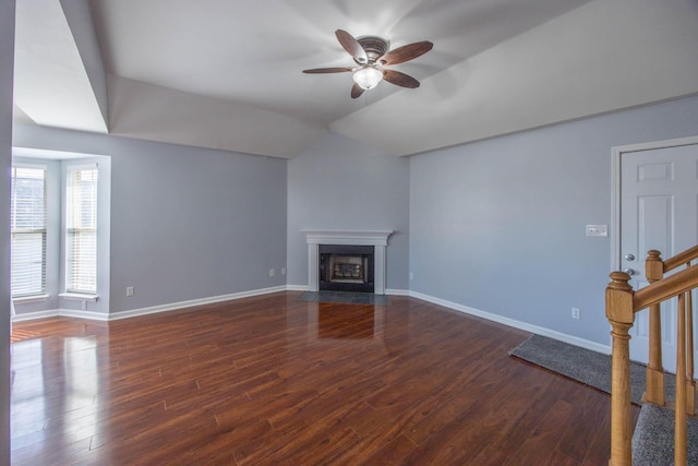 unfurnished living room with stairs, vaulted ceiling, dark wood-style flooring, and a fireplace with flush hearth