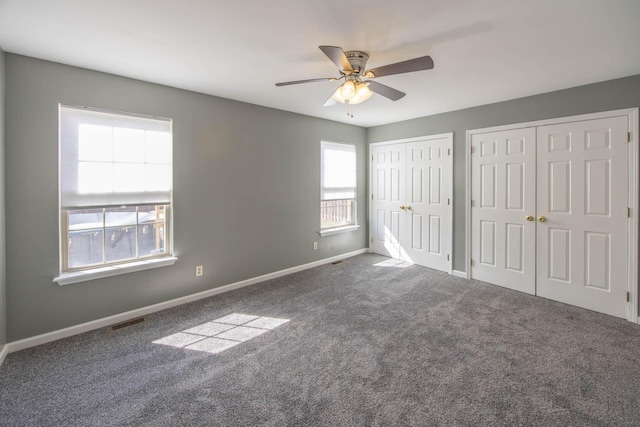 unfurnished bedroom with baseboards, visible vents, multiple closets, and carpet flooring