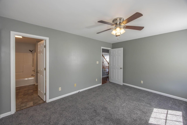 unfurnished bedroom with ceiling fan, dark carpet, connected bathroom, and baseboards