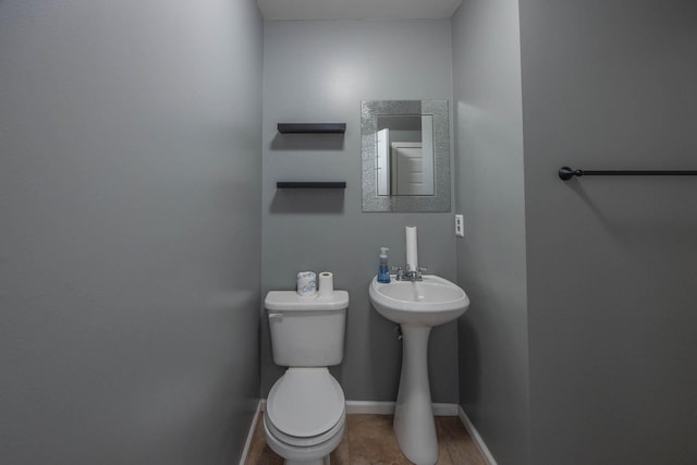 half bathroom featuring toilet and baseboards