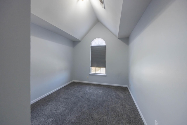 bonus room featuring dark colored carpet, plenty of natural light, lofted ceiling, and baseboards