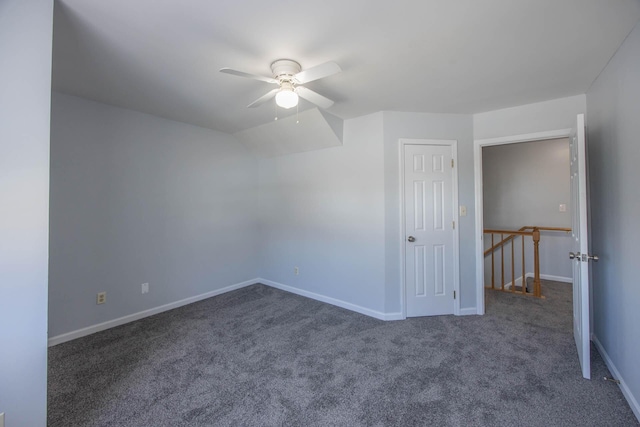 spare room featuring baseboards, dark carpet, and a ceiling fan