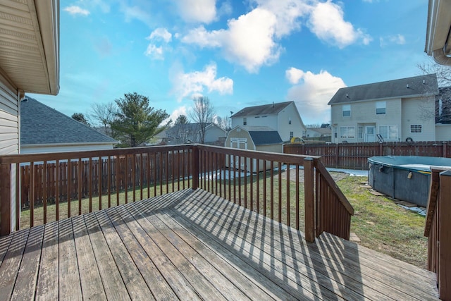 wooden terrace featuring a storage shed, a fenced in pool, a fenced backyard, a residential view, and an outbuilding