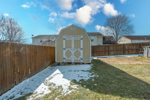 snow covered structure featuring a storage shed, a lawn, an outdoor structure, and a fenced backyard