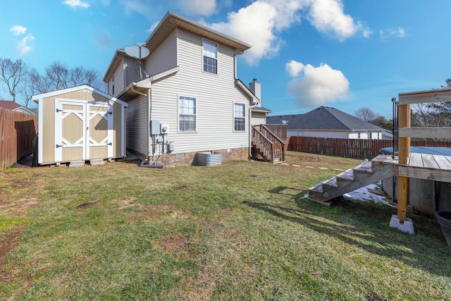 rear view of house featuring a lawn, an outbuilding, fence private yard, stairs, and a shed