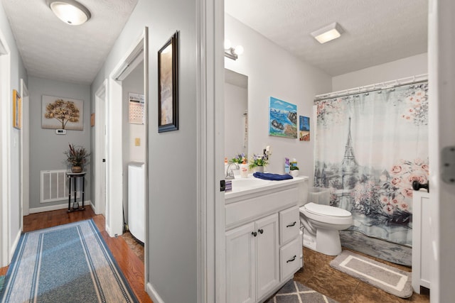 full bath with visible vents, a shower with shower curtain, toilet, vanity, and a textured ceiling