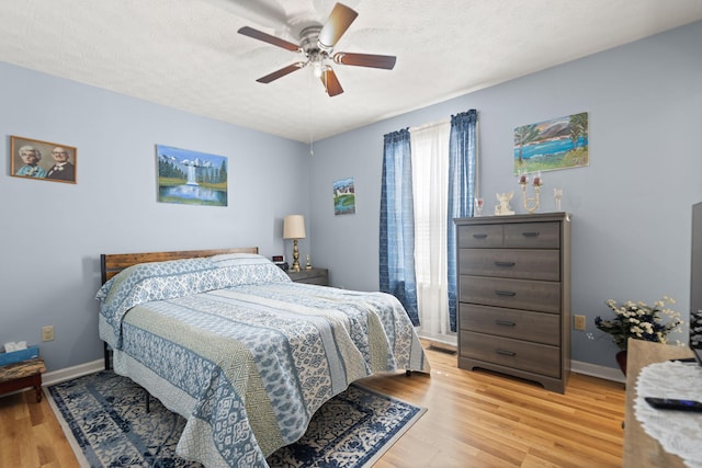 bedroom featuring light wood-type flooring, baseboards, and a textured ceiling