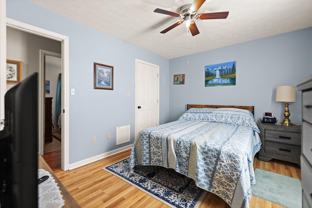 bedroom with a textured ceiling, wood finished floors, a ceiling fan, and baseboards