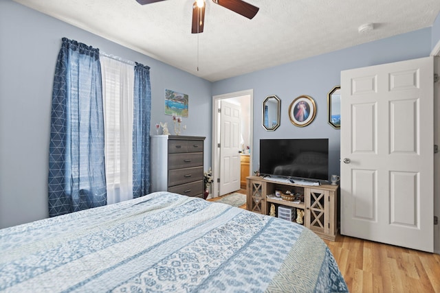 bedroom featuring a ceiling fan, light wood-type flooring, and a textured ceiling