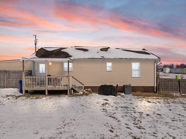 snow covered house with central AC, a wooden deck, and fence