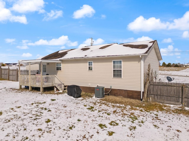 snow covered property featuring a pergola, fence, a wooden deck, and central AC unit