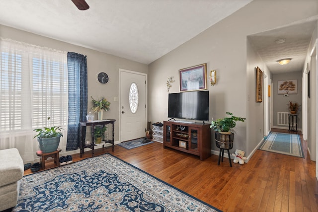 living room with visible vents, baseboards, ceiling fan, wood finished floors, and vaulted ceiling