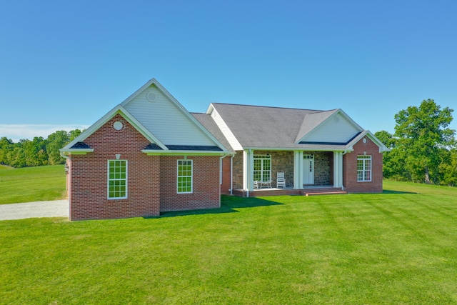 rear view of house featuring covered porch, brick siding, and a yard