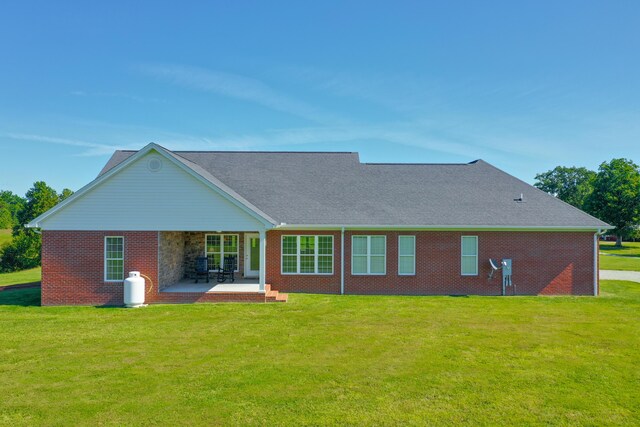 rear view of property with a patio area, a lawn, and brick siding