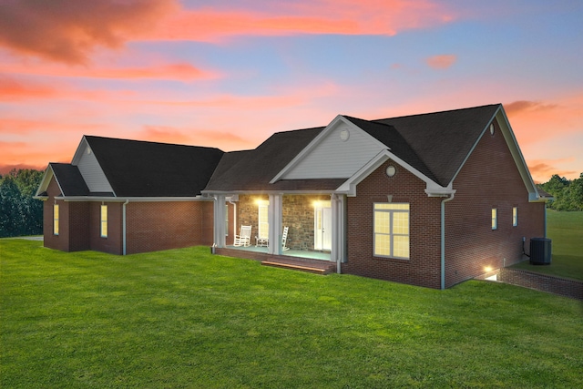 rear view of house featuring central AC, a yard, and brick siding