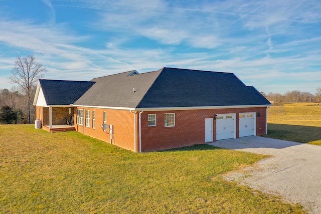 view of side of home with driveway, roof with shingles, a lawn, and brick siding