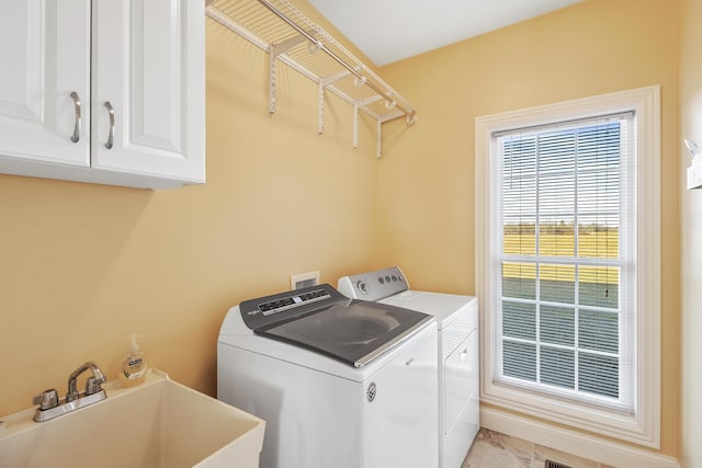 clothes washing area featuring cabinet space, separate washer and dryer, and a sink