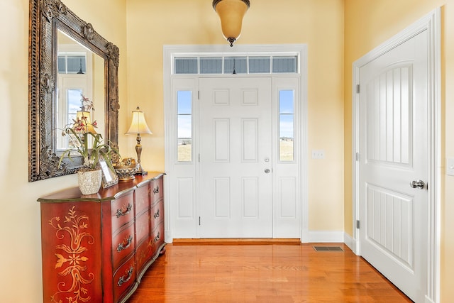 entryway with visible vents, plenty of natural light, baseboards, and wood finished floors