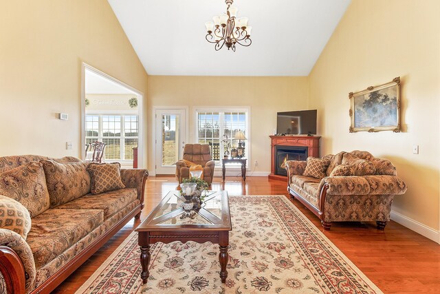 living area featuring a warm lit fireplace, plenty of natural light, wood finished floors, and baseboards