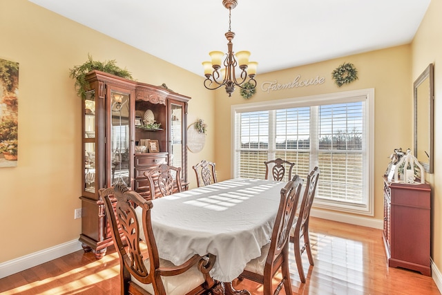 dining room with baseboards, light wood-style flooring, and a notable chandelier