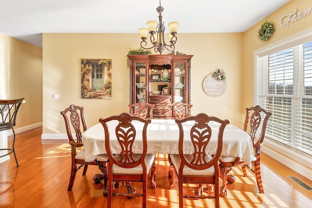 dining space featuring light wood-type flooring, baseboards, visible vents, and a chandelier